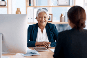 Two people sitting at a desk talking and smiling