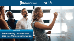 Unconscious Bias is indicated as a very pregnant woman executive leads a standing team meeting of 4 racially diverse members - 2 male and 2 females. The pregnant leader writes “Strategy” on a white board.