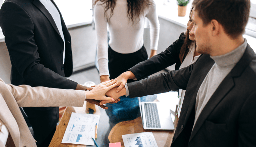 multi-racial coworkers uniting their hands together in a circle